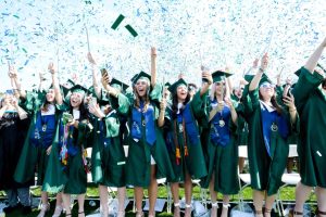 Seniors celebrate at their 2022 graduation while confetti bearing the Colonial Forge school colors shimmer in the air.