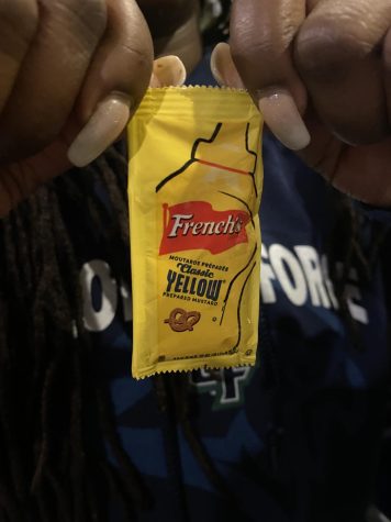 An athlete tears open a packet of mustard to deal with muscle cramps from practice. 