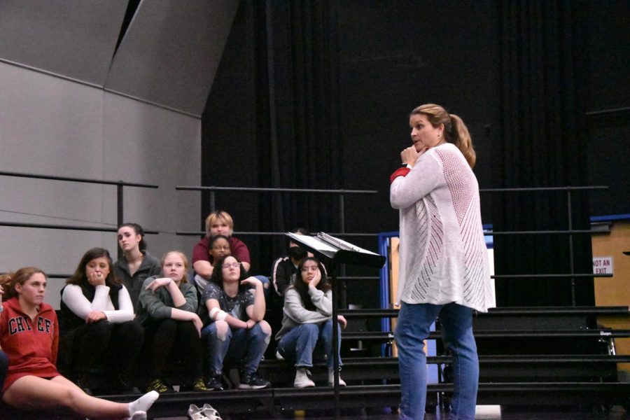 Ms. Barbara Perry instructing choir students during a practice to further develop the students skills.